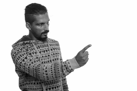Portrait of young handsome bearded Indian man wearing hoodie