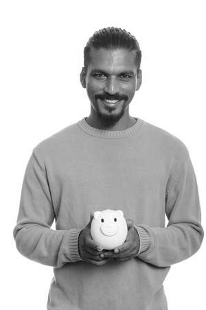 Young happy Indian man holding piggy bankの写真素材