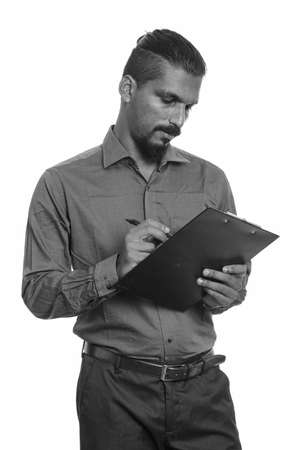Young Indian businessman writing report on clipboardの写真素材