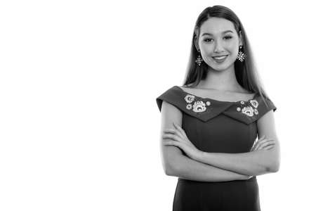 Studio shot of young happy beautiful Asian woman smiling with arms crossedの写真素材