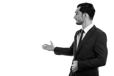 Studio shot of young handsome businessman looking back while showing something on the wallの写真素材