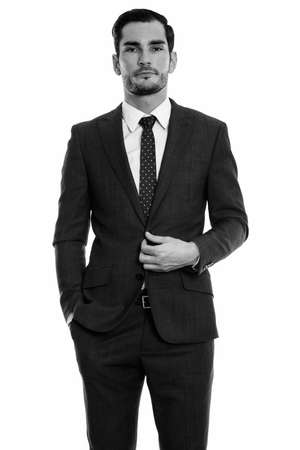 Studio shot of young handsome businessman standing while fixing suitの写真素材