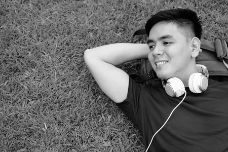 Young handsome Asian man relaxing at the park