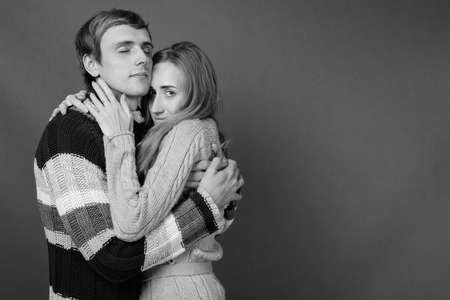 Studio shot of young couple together against gray backgroundの写真素材