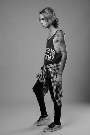 Studio shot of rebellious young man against gray backgroundの写真素材
