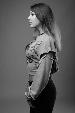Young beautiful rebellious woman against gray backgroundの写真素材