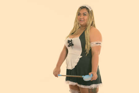 Happy fat Asian cleaning lady smiling while holding toilet brush and wearing sexy maid costumeの写真素材