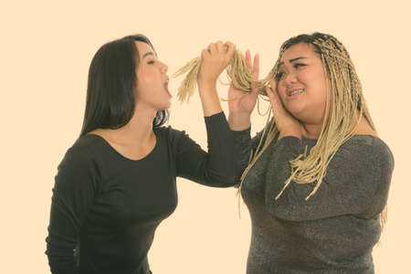 Young Asian transgender woman eating the hair of fat Asian womanの写真素材