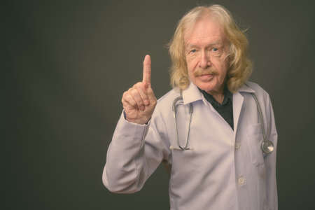 Senior man doctor with mustache against gray backgroundの写真素材