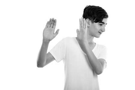 Studio shot of young handsome Persian teenage boy looking away while stopping with both handsの写真素材