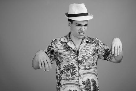 Young handsome tourist man ready for vacation against gray background
