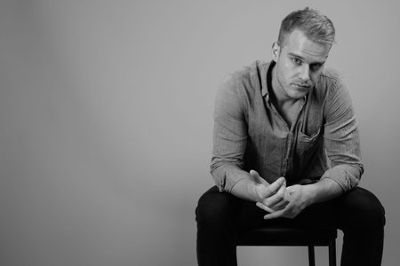 Young handsome businessman with blond hair against gray backgroundの写真素材