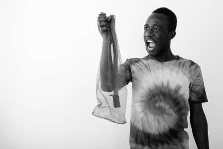 Studio shot of young black African man holding empty exercise mat net against white backgroundの写真素材