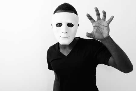 Studio shot of young black African man wearing mask and showing his handの写真素材