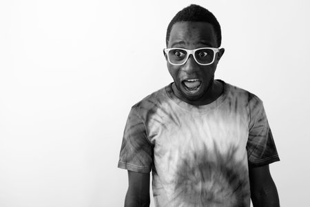 Studio shot of young suprised black African man looking shocked against white background