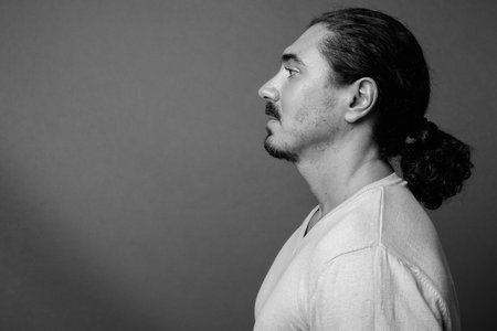 Handsome man with curly hair and mustache against gray background