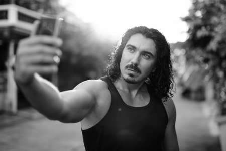 Handsome man with curly hair and mustache in the streets outdoorsの写真素材