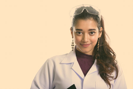 Young beautiful Indian woman doctor wearing protective glasses on head