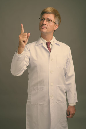 Man doctor with blond hair against gray background