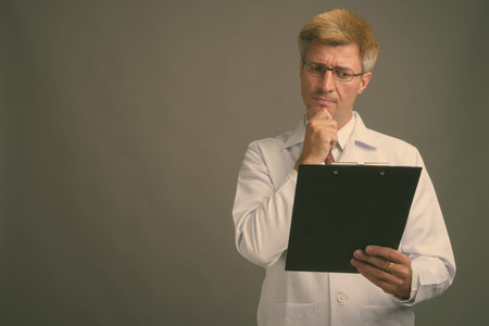 Man doctor with blond hair against gray background