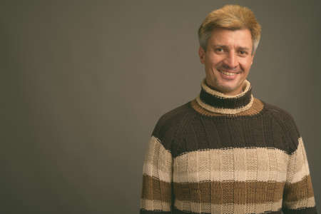 Portrait of happy man with blond hair wearing turtleneck sweaterの写真素材