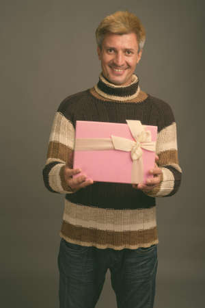 Portrait of happy man with blond hair wearing turtleneck sweaterの写真素材
