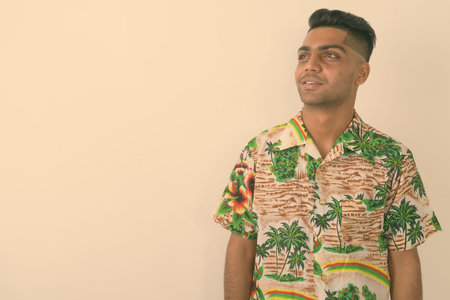 Young Indian tourist man wearing Hawaiian shirt against white background