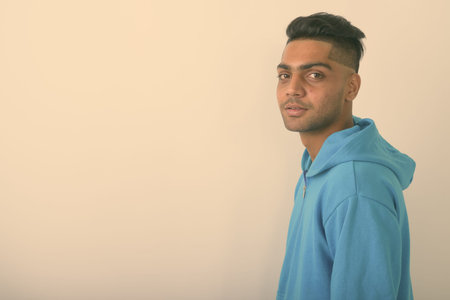 Young Indian man wearing hoodie against white background