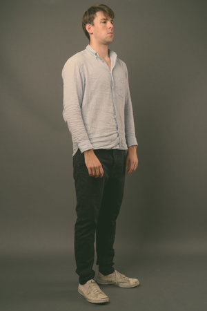 Studio shot of young handsome man against gray background