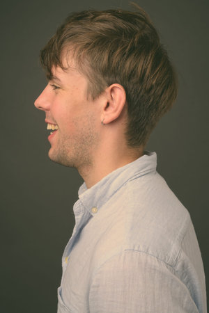 Studio shot of young handsome man against gray background