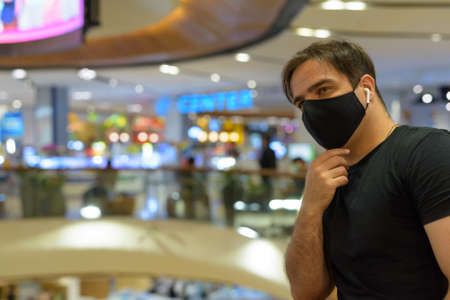 Portrait of Persian man with mask thinking at the mall in the city indoorsの写真素材