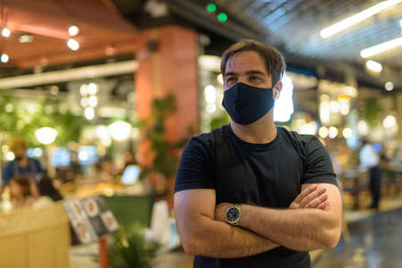 Portrait of Persian man with mask thinking at the mall indoorsの写真素材