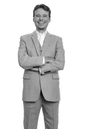 Portrait of happy handsome businessman in suit smiling with arms crossedの写真素材