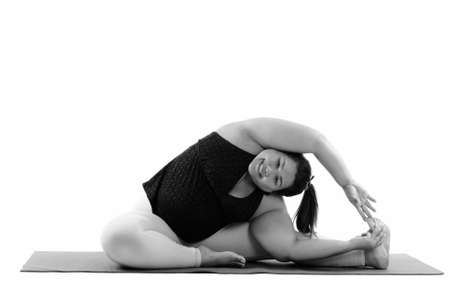 Studio shot of young happy fat Asian woman smiling and reaching her left leg while doing yoga posesの写真素材
