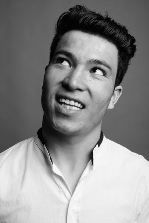 Portrait of young Asian businessman against gray background