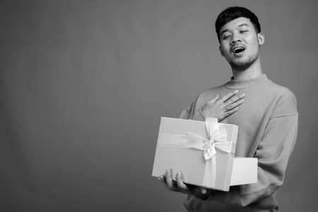 Portrait of young Asian man against gray backgroundの写真素材