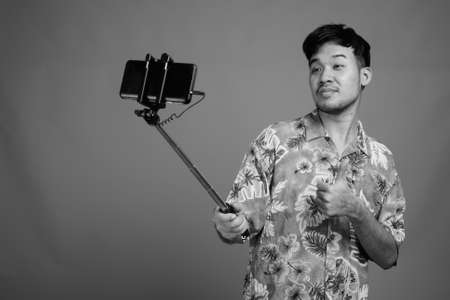 Young Asian tourist man ready for vacation against gray backgroundの写真素材