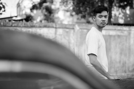 Young Asian man with rusty old car in the streets outdoors