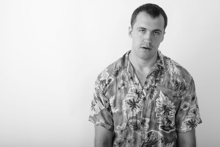 Studio shot of young muscular tourist man looking tired against white background