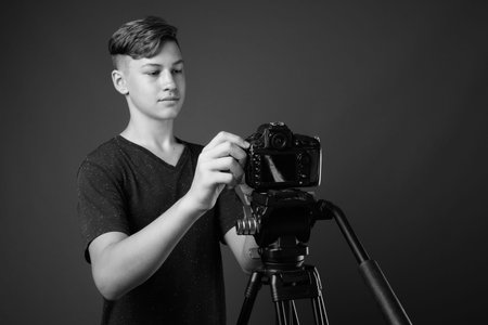 Studio shot of young handsome teenage boy against gray background