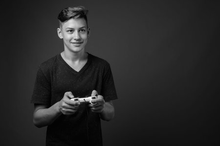 Studio shot of young handsome teenage boy against gray background