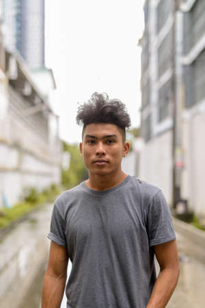 Young Asian man with curly hair in the streets outdoorsの写真素材