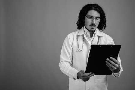 Handsome man doctor with mustache against gray backgroundの写真素材