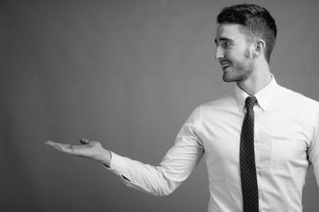 Portrait of young handsome businessman against gray backgroundの写真素材