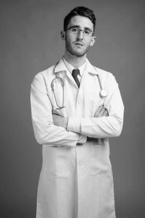 Young handsome man doctor wearing eyeglasses against gray backgroundの写真素材