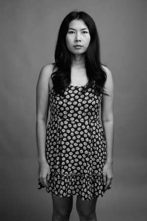 Asian woman wearing dress against gray backgroundの写真素材