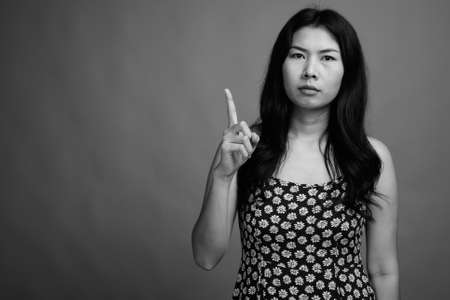 Asian woman wearing dress against gray backgroundの写真素材