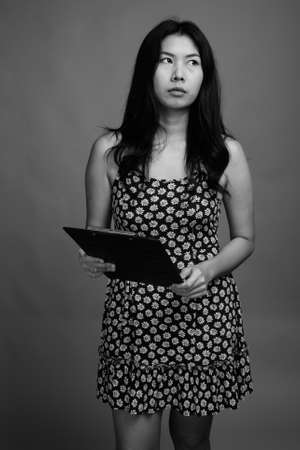 Asian woman wearing dress against gray backgroundの写真素材