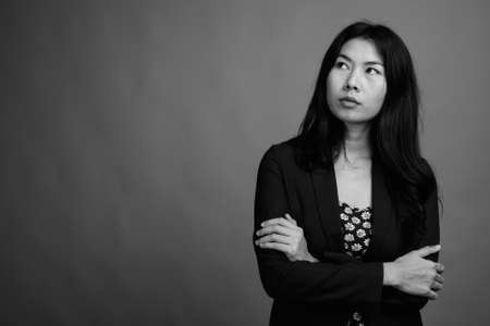 Asian woman wearing dress and cardigan sweater against gray backgroundの写真素材