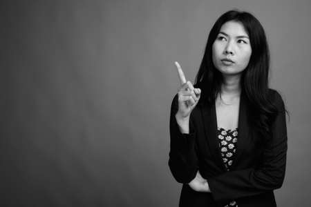 Asian woman wearing dress and cardigan sweater against gray backgroundの写真素材